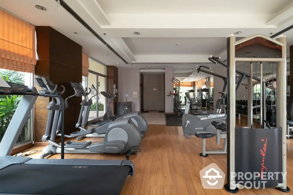 Luxurious gym with modern fitness equipment and wooden flooring in upscale residential property.