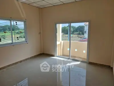 Spacious room with large windows and balcony access, offering natural light and scenic views.