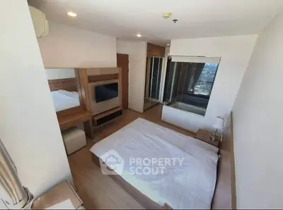 Spacious bedroom with modern furnishings and large window offering city views.