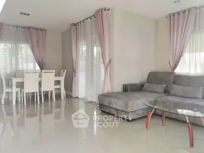 Spacious living room with modern decor and dining area, featuring elegant curtains and sleek furniture.