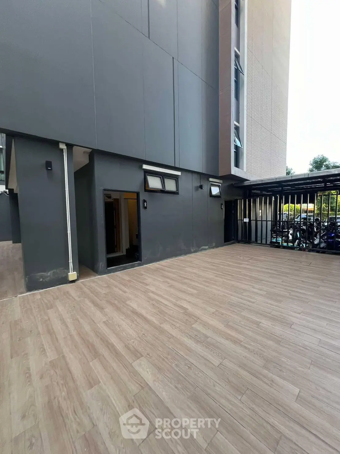 Modern building exterior with spacious wooden deck and parking area