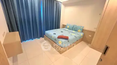 Cozy bedroom with modern furnishings and blue floral bedding, featuring ample natural light and sleek tile flooring.
