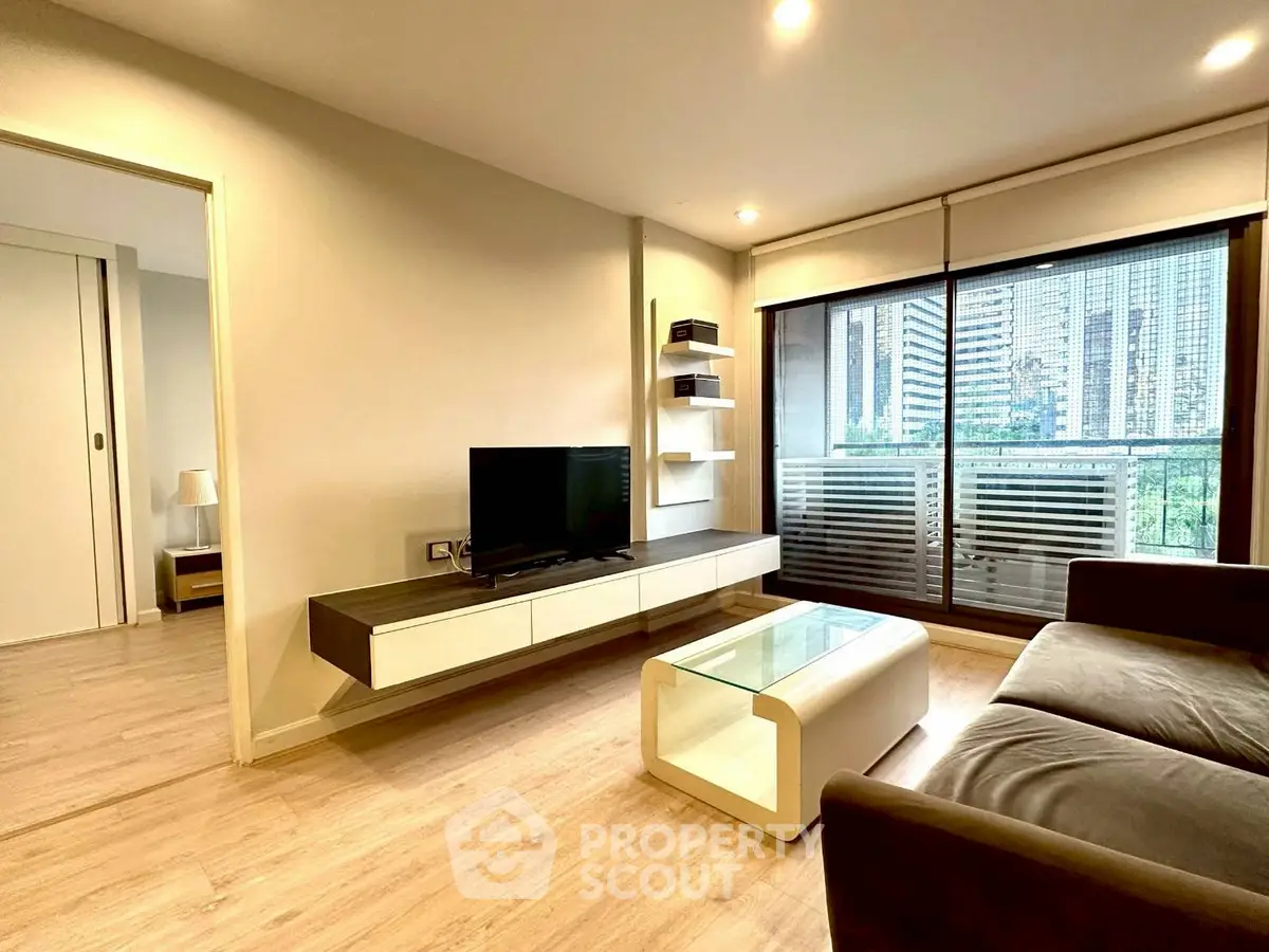 Modern living room with sleek furniture and city view balcony in luxury apartment.