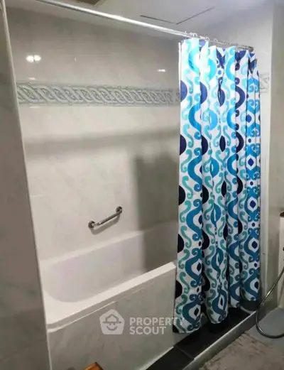 Modern bathroom with stylish blue patterned shower curtain and bathtub.