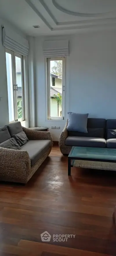 Cozy living room with stylish wicker furniture and wooden flooring.