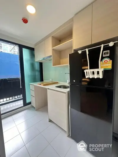 Modern kitchen with sleek cabinetry and large refrigerator in a bright apartment