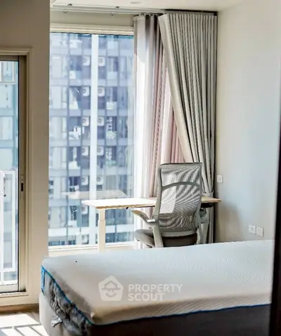 Modern bedroom with large window and city view, featuring a comfortable bed and stylish chair.