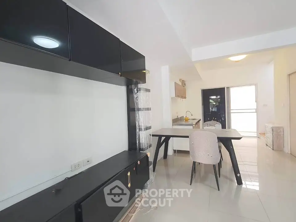 Modern open-plan living area with sleek black cabinetry and stylish dining setup.
