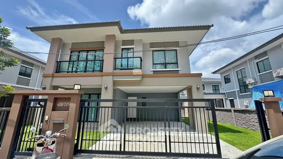 Modern two-story house with gated driveway and lush green lawn