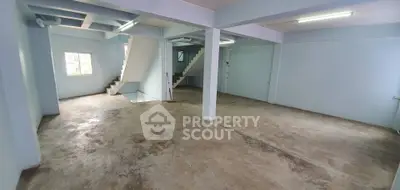 Spacious open-plan interior with concrete flooring and staircase, ideal for customization.