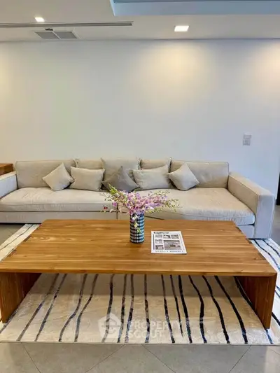 Modern living room with stylish sofa and wooden coffee table, featuring elegant decor.