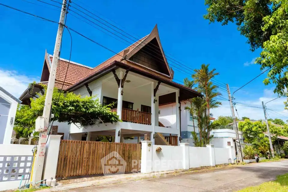 Charming two-story house with traditional roof and lush greenery in a serene neighborhood.