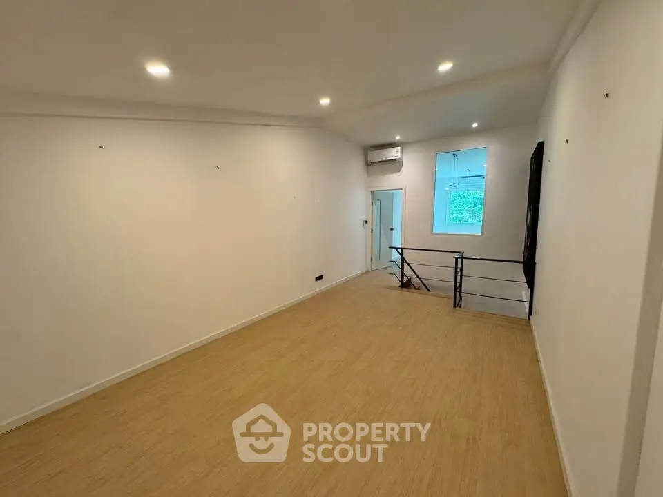 Spacious interior room with wooden flooring and bright lighting, ideal for versatile living space.