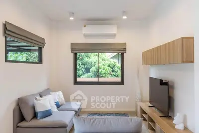 Modern living room with sleek furniture and large window offering lush green views.