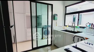 Modern kitchen with sleek design, featuring large windows and integrated appliances.