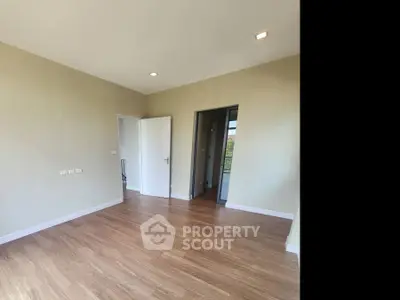 Spacious empty room with wooden flooring and natural light, perfect for customization.