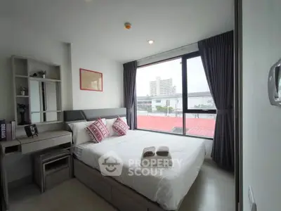 Modern bedroom with large window and city view, featuring stylish decor and ample natural light.