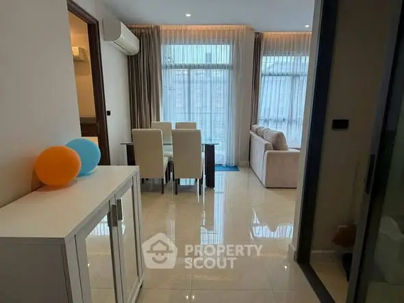 Spacious living room with elegant dining area and large windows in modern apartment.