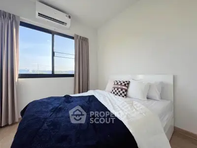Cozy bedroom with modern decor and large window offering natural light.