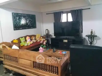 Cozy living room with plush toys, wooden furniture, and large TV, perfect for family relaxation.