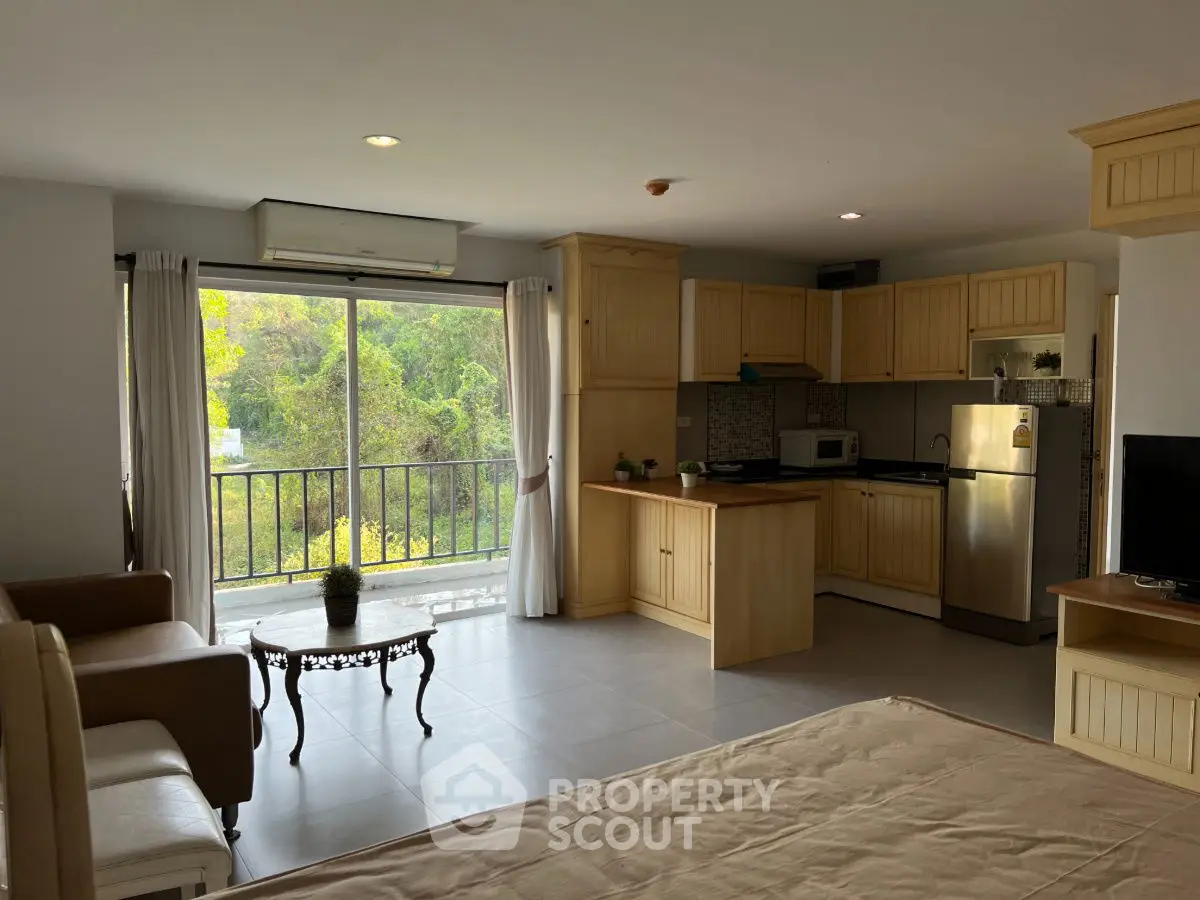 Spacious open-plan living area with modern kitchen and balcony view.