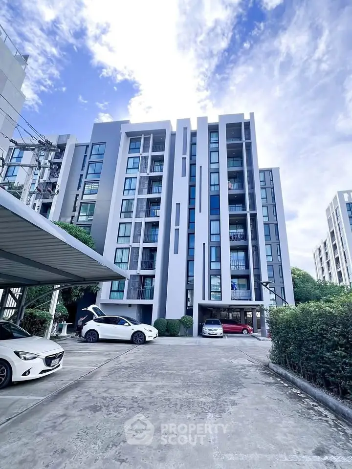 Modern apartment building with sleek design and ample parking space in urban setting.
