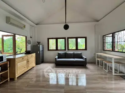 Spacious living room with modern decor and large windows offering lush garden views.