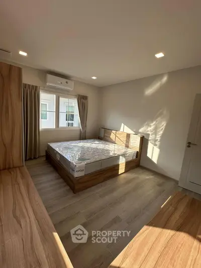 Spacious bedroom with natural light and modern wooden flooring