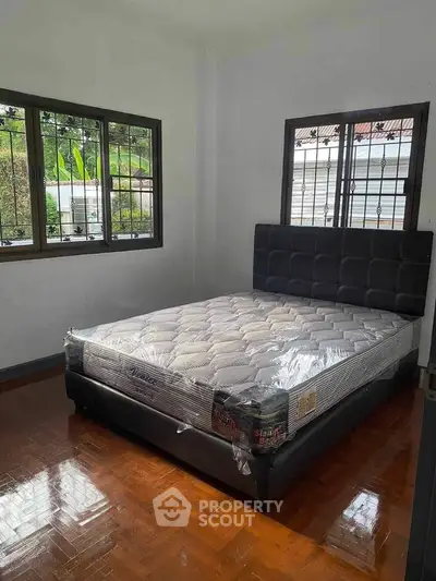 Cozy bedroom with new mattress and hardwood floors, perfect for restful nights.