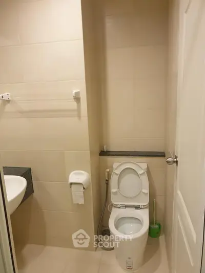 Modern bathroom with sleek fixtures and neutral tiles, featuring a toilet and sink.