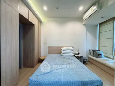 Modern bedroom with sleek design and natural light, featuring built-in wardrobe and cozy seating area.