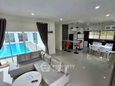 Luxurious open-plan living room with pool view and modern kitchen