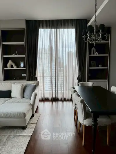Elegant living room with city view, featuring plush sofa and chic dining area.