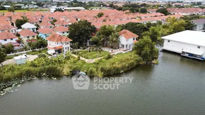 Scenic aerial view of waterfront residential community with red-roofed houses and lush greenery.