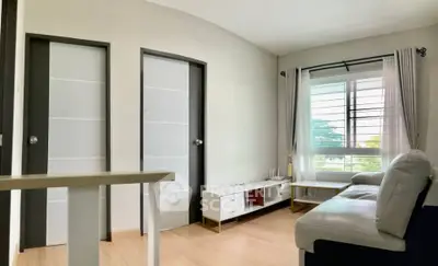 Modern living room with sleek furniture and large window offering natural light.
