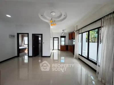 Spacious open-plan living room with modern kitchen and large windows for natural light.