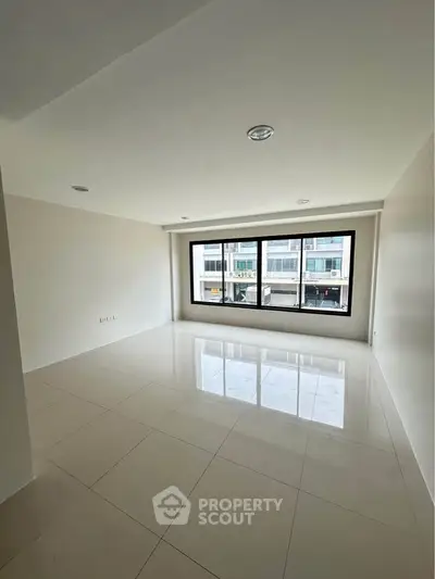 Spacious empty room with large window and glossy tiled floor, ideal for customization.
