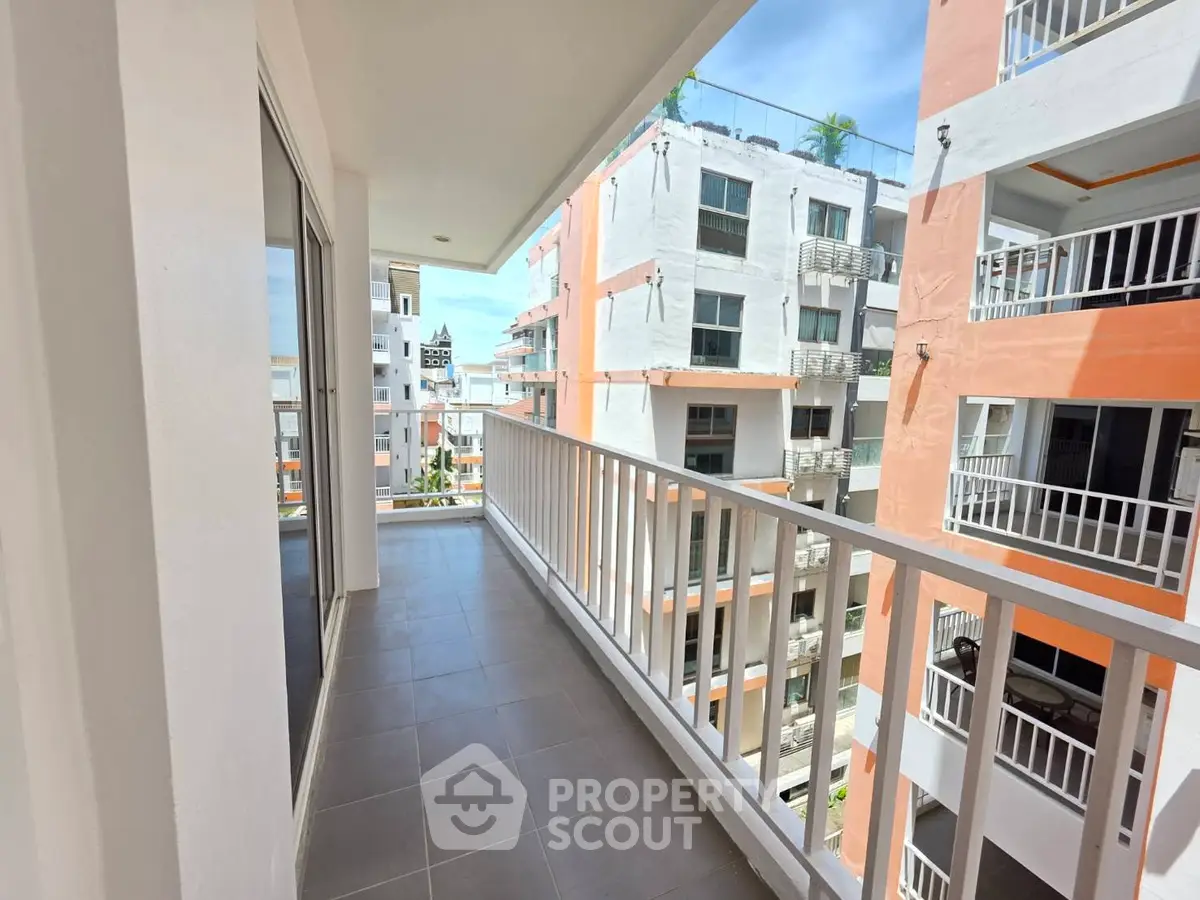 Spacious balcony with modern railing and city view in vibrant apartment complex
