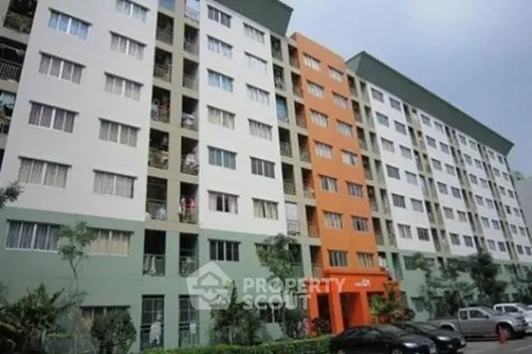 Modern multi-story apartment building with colorful facade and lush greenery.