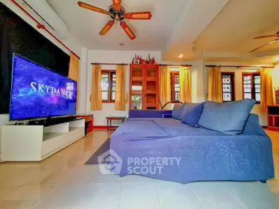 Spacious living room with modern decor and large TV, perfect for entertainment.