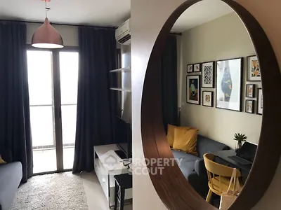 Stylish living room with modern decor and cozy seating area, featuring a large mirror and natural light.