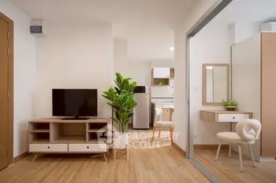 Modern living room with TV, stylish furniture, and open kitchen layout in a cozy apartment.