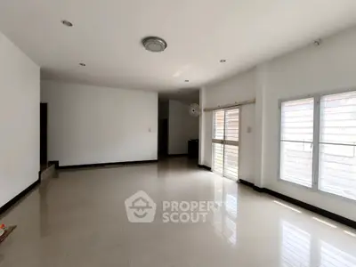 Spacious empty living room with large windows and tiled flooring