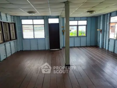 Spacious empty room with wooden floors and large windows in a rustic home