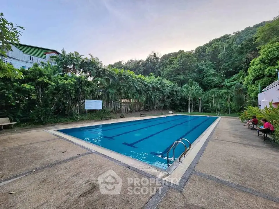 Serene outdoor swimming pool surrounded by lush greenery, perfect for relaxation and leisure.