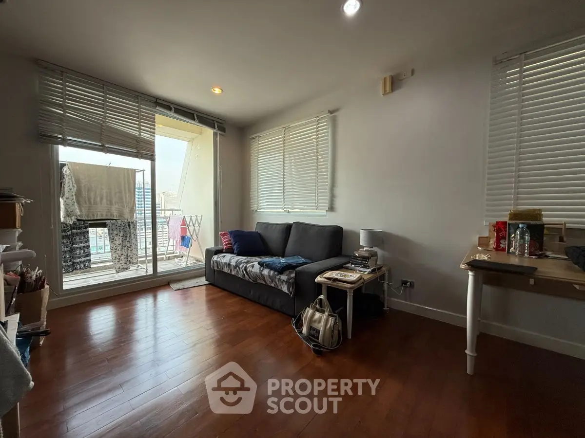 Cozy living room with balcony access and wooden flooring, perfect for urban living.