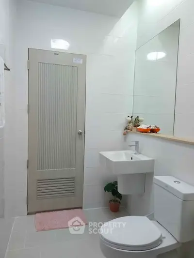 Modern bathroom with sleek fixtures and minimalist design, featuring a wall-mounted sink and toilet.
