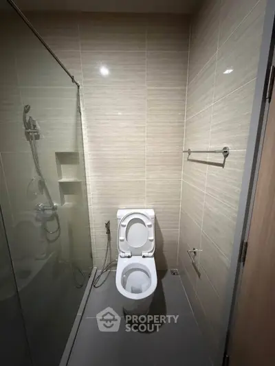 Modern bathroom with sleek shower and toilet in contemporary apartment.