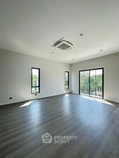 Spacious empty room with large windows and modern flooring, perfect for customization.