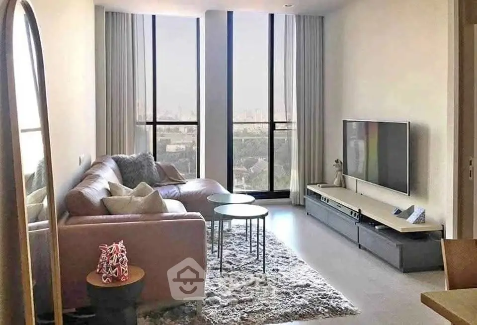 Modern living room with large windows and stylish furniture in a high-rise apartment.